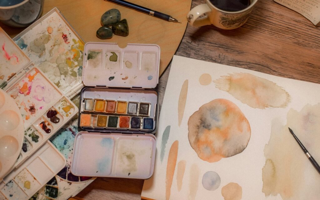 An artist's palette and brushes set out on a desk, untouched.
